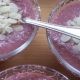 Chia pudding van aardbeien in glazen ijskommetjes met amandelschilfers erop.