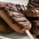 Zelfgemaakte mokka-ijsjes op stokjes met krokante chocolade decoratie - op een wit bord